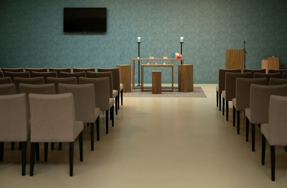 Aula van Uitvaartcentrum Melis met rijen stoelen, kaarsen en een houten spreekgestoelte